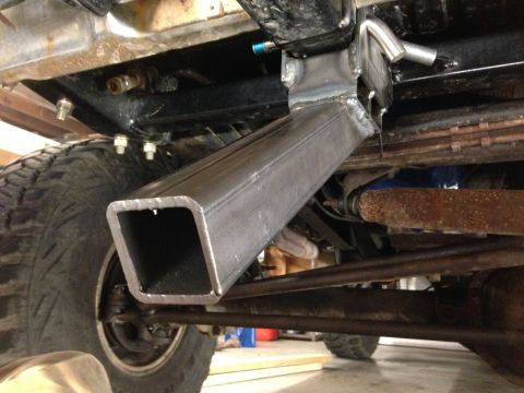 1979 Ford Bronco - The underside of a vehicle shows a custom fabricated steel bracket welded to the frame and extending downwards, with a large square metal t…