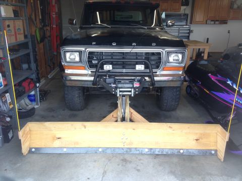 1979 Ford Bronco - A black 1979 Ford Bronco with a wooden plow attached to the front is parked in a garage next to a snowmobile.