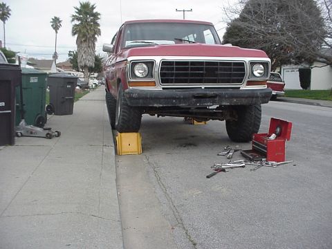 1978 Ford Bronco - A red 1978 Ford Bronco is parked on yellow blocks in front of a driveway, with tools scattered on the pavement.