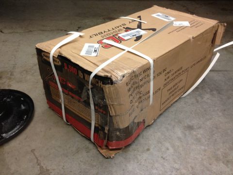 1979 Ford Bronco - A large Smittybilt winch box is secured with white straps on a concrete floor. The box has visible text indicating it is a 9,500 lb electri…