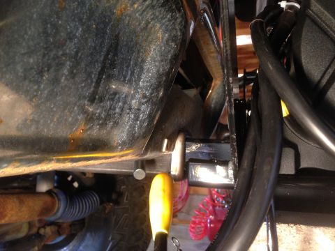 1979 Ford Bronco - A close-up view of the undercarriage of a vehicle, showing a hitch receiver with a yellow handle inserted. Rust is visible on the vehicle's…