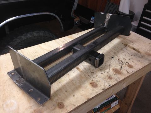 1979 Ford Bronco - A custom-fabricated hitch receiver mount is shown resting on a wooden workbench. The mount is constructed from dark metal tubing and featur…