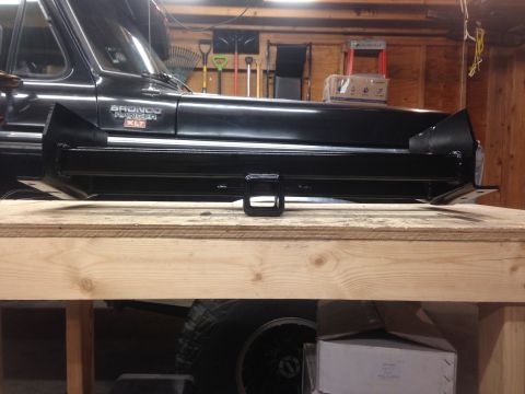 1979 Ford Bronco - A black Ford Bronco sits behind a newly installed black trailer hitch receiver mounted on a wooden workbench. The trailer hitch is a heavy-…
