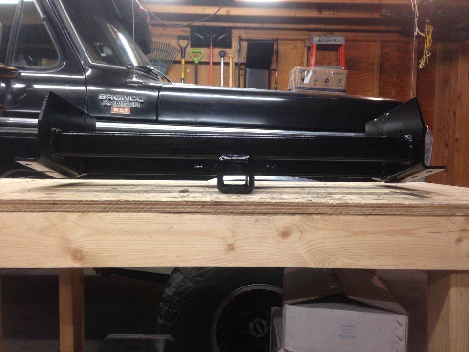 Black Ford Bronco with a new trailer hitch receiver on a workbench.