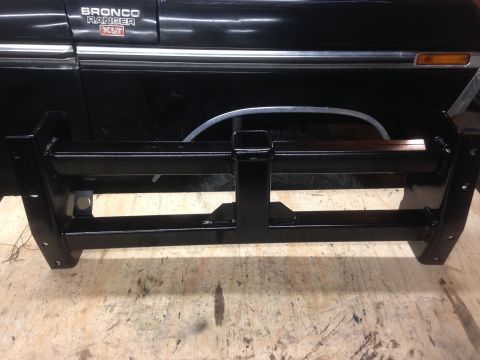 1979 Ford Bronco - A black, custom-fabricated front bumper is shown in the foreground, with the lower portion of a black 1979 Ford Bronco visible behind it. T…