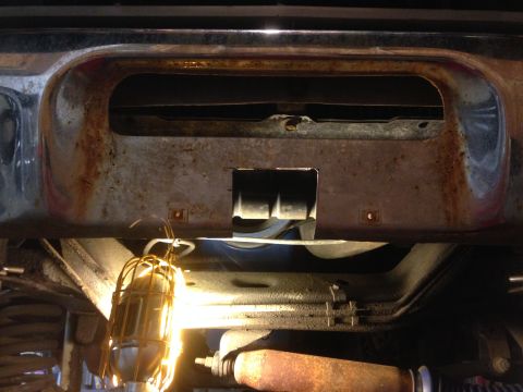1979 Ford Bronco - This is a close-up, low-angle view of the rusted front bumper area of a vintage vehicle, possibly a truck or SUV. A work light illuminates…