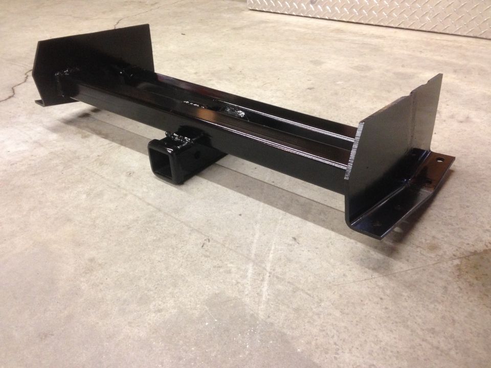 Black trailer hitch receiver with mounting plates on a concrete floor.
