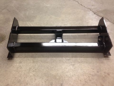 1979 Ford Bronco - A black winch mount bracket is shown on a concrete floor. The part features welded construction and mounting points for attachment.
