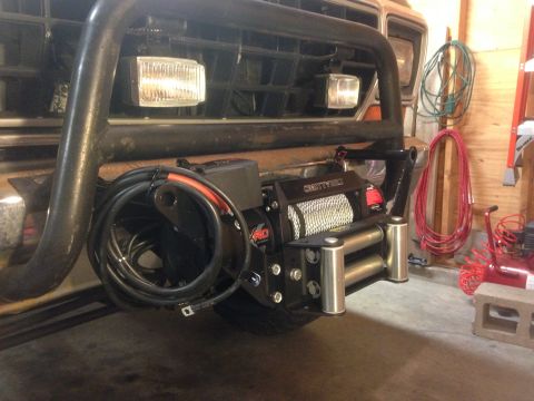 1979 Ford Bronco - A Superwinch is mounted to the front of a vehicle, behind a heavy-duty brush guard.