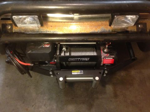 1979 Ford Bronco - A Smittybilt winch is installed on the front of a vehicle, with visible wiring and caution labels.