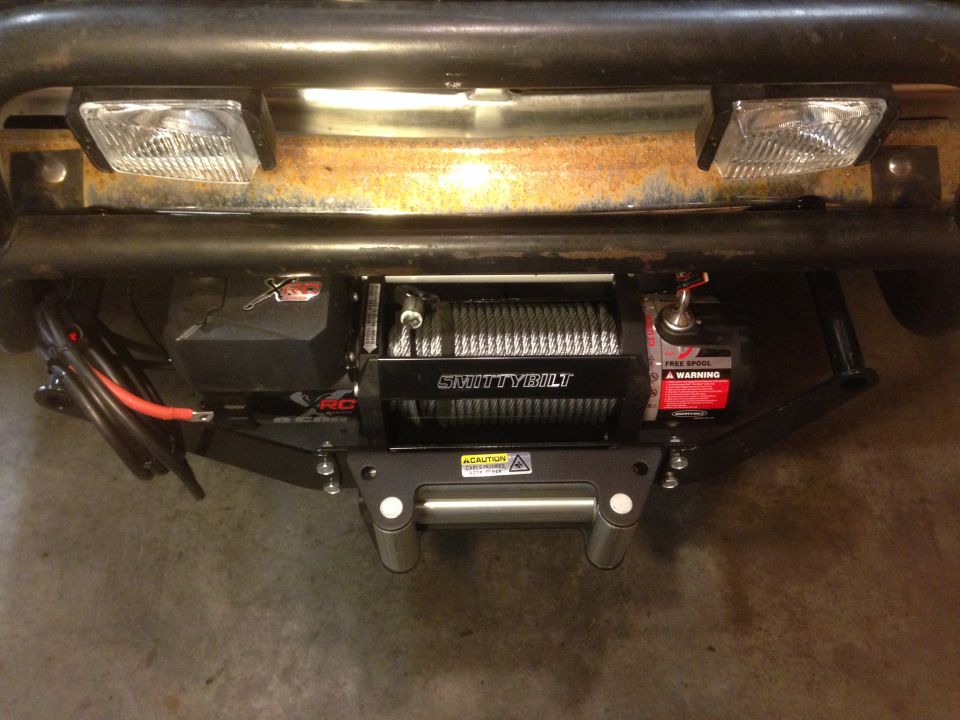 Winch mounted on a vehicle's front bumper with two square headlights above