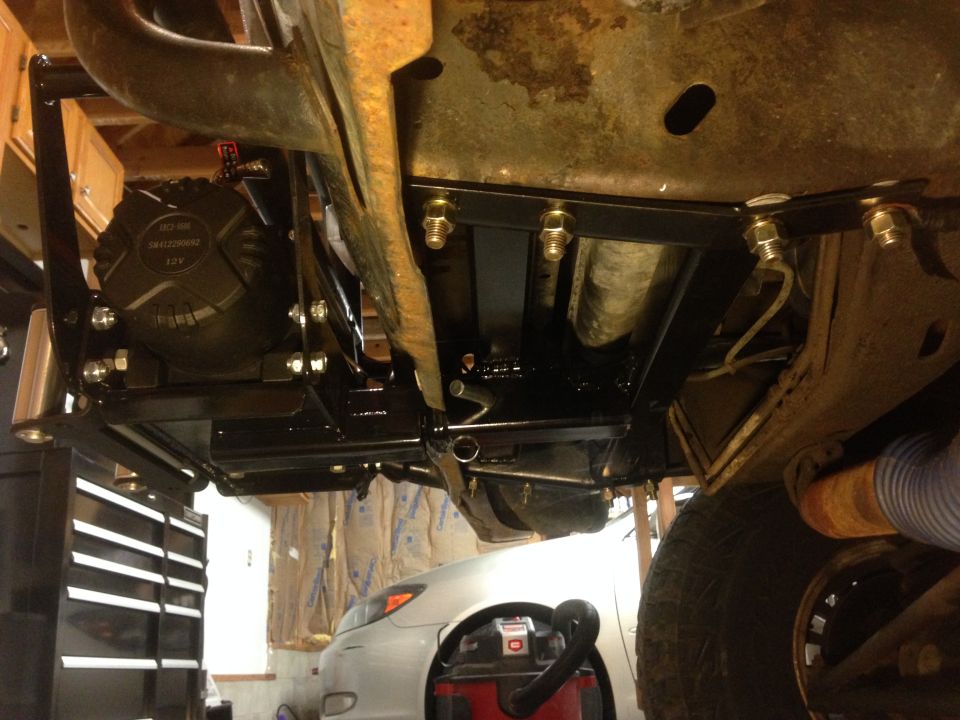 Winch mount assembly bolted to vehicle frame, with part of a tire visible