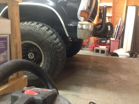 1979 Ford Bronco - The front passenger side of a black Ford Bronco is shown, large off-road tires and a winch mount assembly.