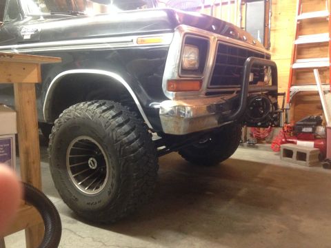 1979 Ford Bronco - A black 1979 Ford Bronco is parked indoors, a winch mount and off-road tires.