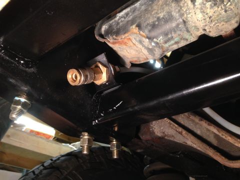 1979 Ford Bronco - Close-up of an air compressor quick disconnect fitting attached to the vehicle's frame, with a tire visible below.