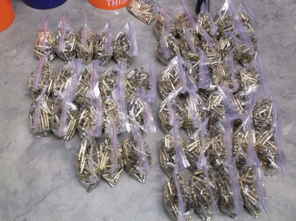Bags of brass bullet casings on a concrete floor.