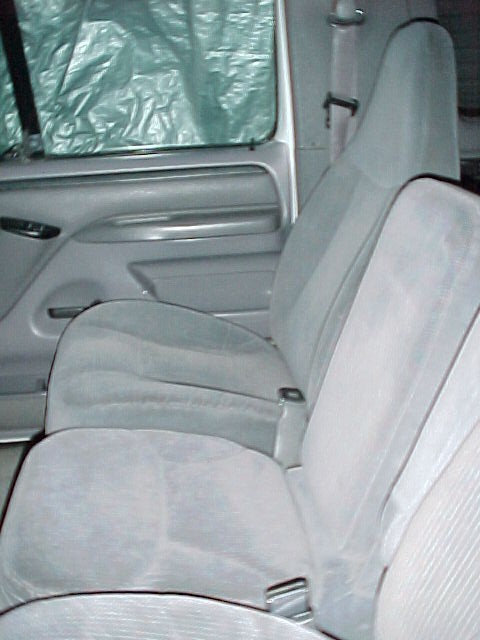 1996 Ford Bronco - Interior view of a vehicle's seats and door panel, with the window covered by a tarp.