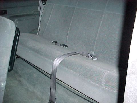 1996 Ford Bronco - The interior of a vehicle shows a gray rear bench seat with seatbelts.