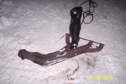 1973 Ford F-250 - A reciprocating saw is cutting through a rusty exhaust manifold lying on the snow.