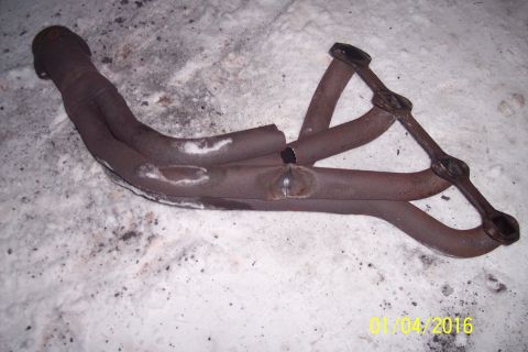 1973 Ford F-250 - A rusty exhaust manifold with four pipes is shown lying on a snowy surface. One of the pipes appears to be broken and has been welded.