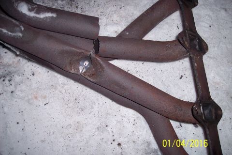 1973 Ford F-250 - A close-up view of a rusty exhaust manifold with a significant crack and hole, resting on a snowy surface. The date "01/04/2016" is visible…