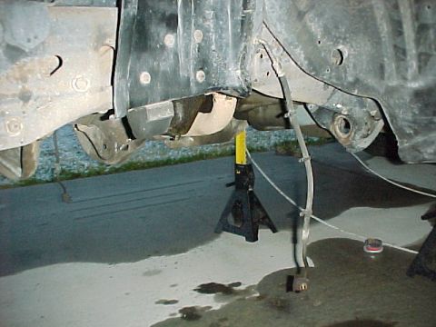 1996 Ford Bronco - Vehicle frame and suspension components are supported by jack stands, with a brake line visible.