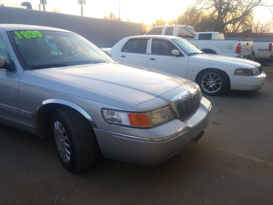 Silver sedan front quarter at a car lot with price sign
