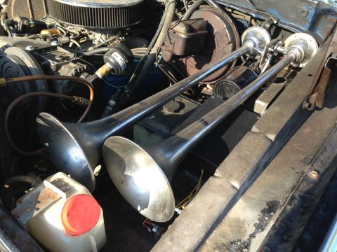 1979 Ford Bronco - A close-up view of the engine bay of a classic vehicle, featuring a dual-trumpet air horn system mounted prominently. The engine components…