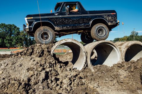 1979 Ford Bronco - A black 1979 Ford Bronco, nicknamed "Black Betty", navigates an off-road obstacle course featuring large concrete pipes and dirt mounds.
