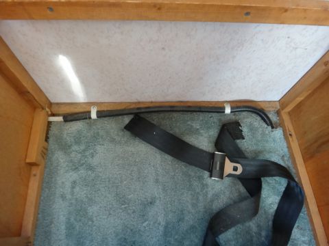 1995 Chevrolet P30 1 Ton - Step Van - A black seatbelt is laid out on a blue carpeted floor inside a wooden structure. A black corrugated tube is secured to the ceiling with whi…