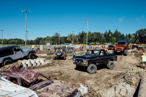 1979 Ford Bronco - A black 1970s Ford pickup truck navigates a muddy obstacle course in front of spectators. The truck is positioned on a dirt mound with othe…