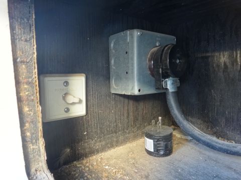 1995 Chevrolet P30 1 Ton - Step Van - A close-up view shows a park cable hookup with a switch and a 30-amp RV power inlet with a connected power cord and plug, mounted on a wood…