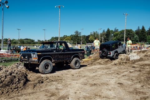 1979 Ford Bronco - A black Ford Bronco is pulling a silver Jeep Wrangler through a dirt obstacle course on a sunny day. Both vehicles are heavily modified for…