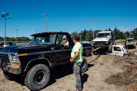 1979 Ford Bronco - A man in a lime green shirt stands next to a mud-splattered black Ford pickup truck. The truck's driver, wearing a baseball cap, looks out…