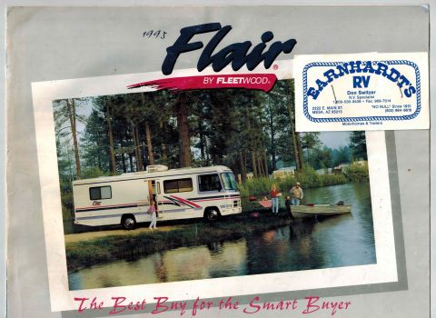 1995 Chevrolet P30 1 Ton - Step Van - A 1995 Fleetwood Flair RV is parked by a lake with a family nearby. The RV is white with red and blue accents and has the Flair logo on the…