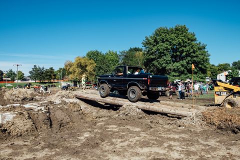 1979 Ford Bronco - A black 1970s Ford Bronco drives over a log obstacle course on a sunny day. The off-road event appears to be taking place in a park or fiel…
