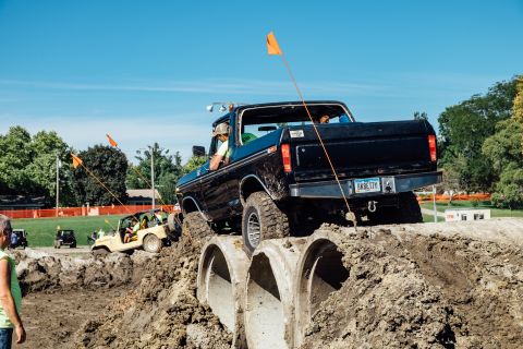 1979 Ford Bronco - A black Ford pickup truck navigates an obstacle course, driving over large concrete pipes on a dirt track under a clear blue sky. The truck…
