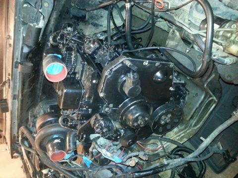 1994 Ford Bronco - A close-up view of a black diesel engine with a turbocharger and intake pipes. The engine bay is cluttered with hoses, wires, and other com…