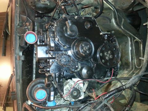 1994 Ford Bronco - A close-up, top-down view of a black engine block with various pulleys and a turbocharger visible. The engine bay appears to be from a Ford…