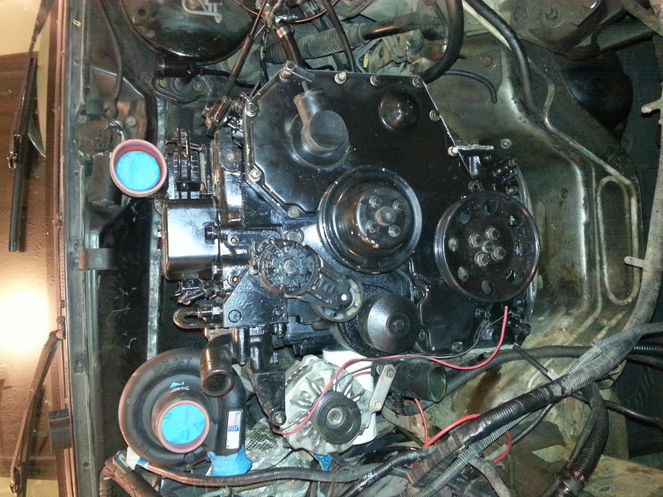 Engine bay of a 1994 Ford Bronco with turbocharger and black engine block.