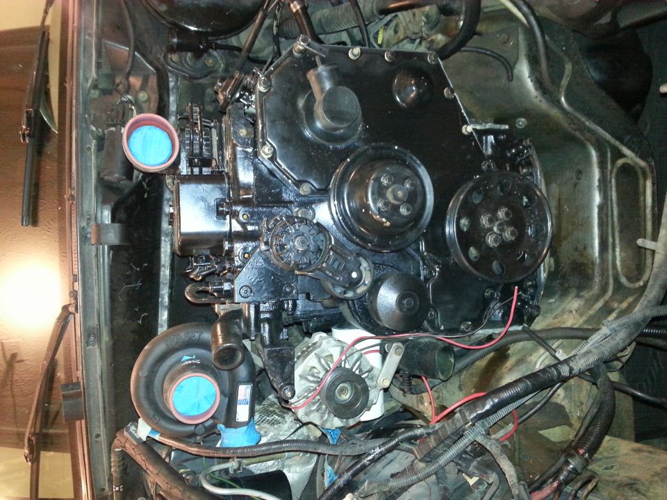 Engine bay with black diesel engine, turbocharger, and blue intake filters.