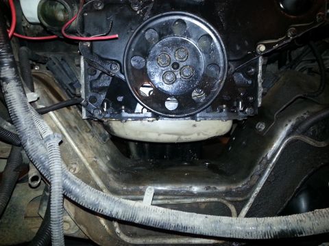 1994 Ford Bronco - A close-up view of the engine bay of a 1994 Ford Bronco, focusing on the lower engine block and surrounding frame components. The area appe…