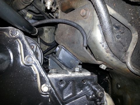 1994 Ford Bronco - This image shows the engine bay of a 1994 Ford Bronco, focusing on the transmission mount and surrounding components. The black rubber moun…