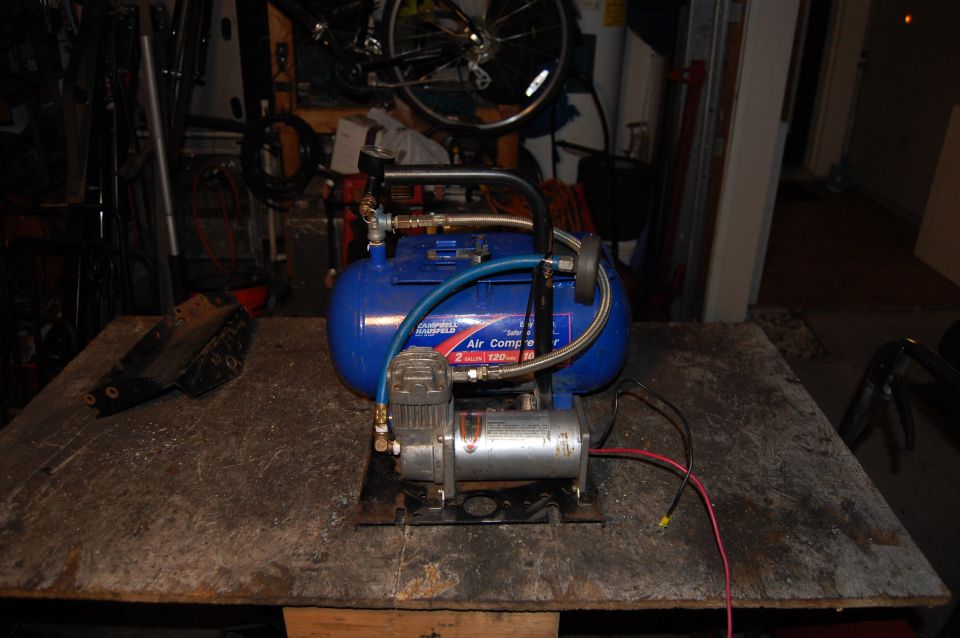 Blue Campbell Hausfeld air compressor with silver motor on a wooden workbench.