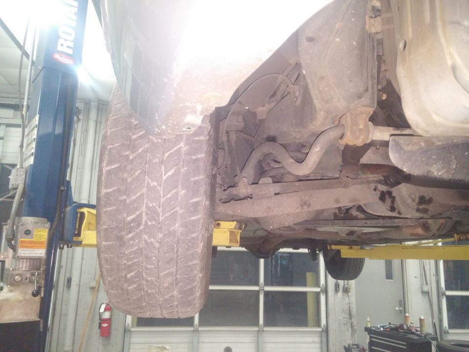 Photo of vehicle front suspension and tire on a lift