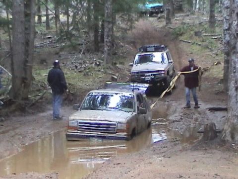 1994 Ford Explorer - Two SUVs navigating a muddy trail, one is deeply stuck in a water-filled rut.