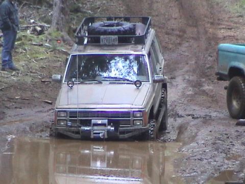 1994 Ford Explorer - Off-road Jeep Cherokee navigates a muddy trail, getting stuck in a deep puddle.