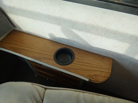 1995 Chevrolet P30 1 Ton - Step Van - A wooden shelf with a black cup holder is mounted on the interior wall of a vehicle, above a light-colored seat. The shelf appears to be a…