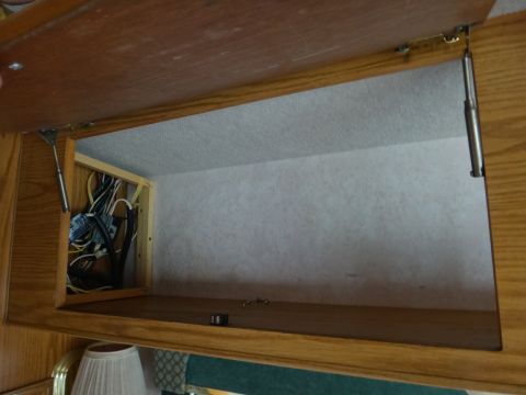 1995 Chevrolet P30 1 Ton - Step Van - An open overhead cabinet in a vehicle reveals a cluttered compartment filled with electrical wiring and components. The cabinet is made of…