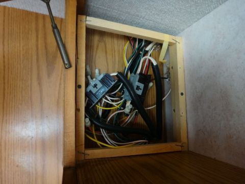 1995 Chevrolet P30 1 Ton - Step Van - A close-up view of a wooden cabinet interior containing a bundle of electrical wires and connectors. The wires are of various colors includ…